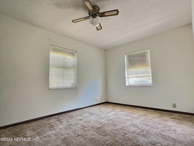 carpeted spare room with a textured ceiling and ceiling fan