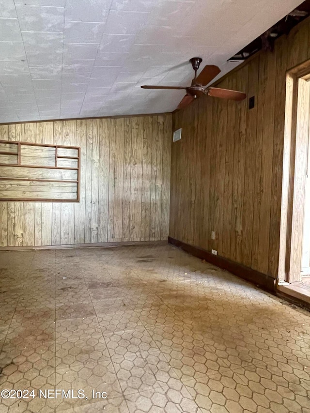 spare room with ceiling fan and wooden walls