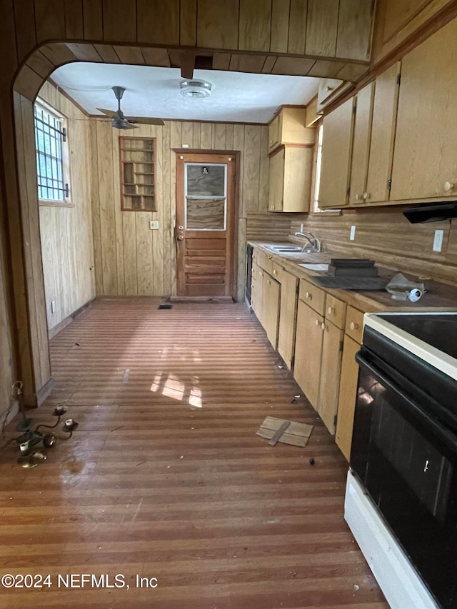 kitchen with black electric range oven, hardwood / wood-style floors, ceiling fan, sink, and wooden walls