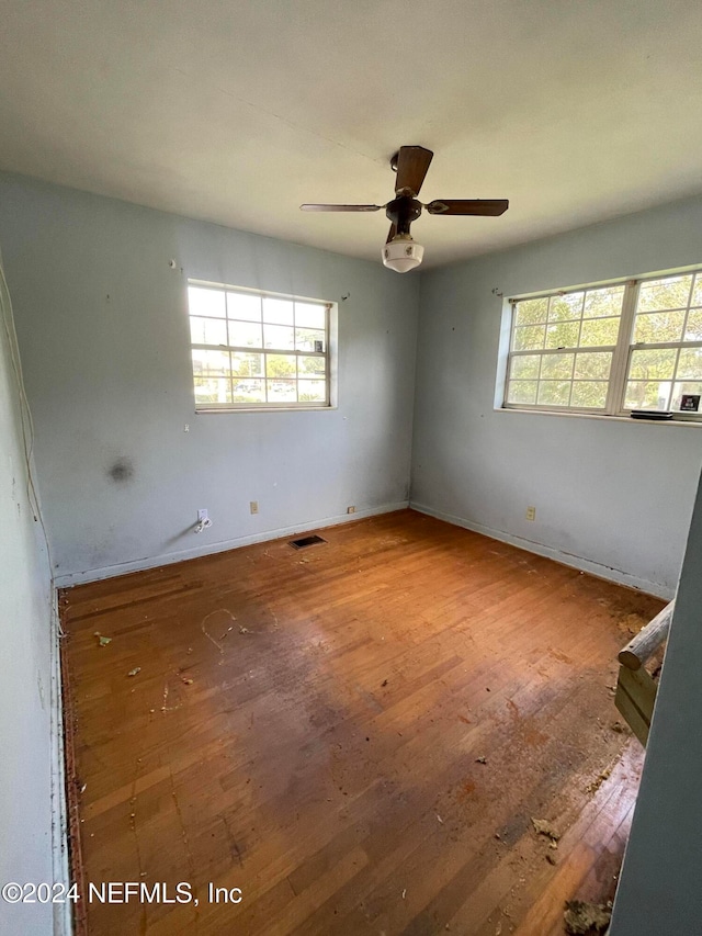 unfurnished room with ceiling fan, a wealth of natural light, and hardwood / wood-style floors