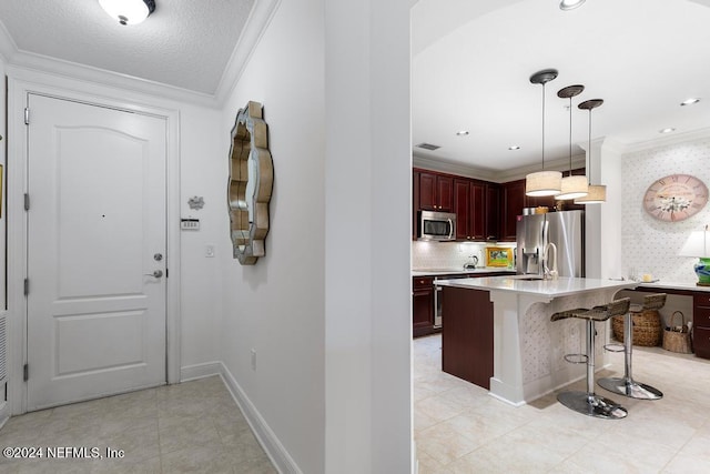 kitchen with crown molding, a breakfast bar, decorative light fixtures, light tile patterned floors, and appliances with stainless steel finishes