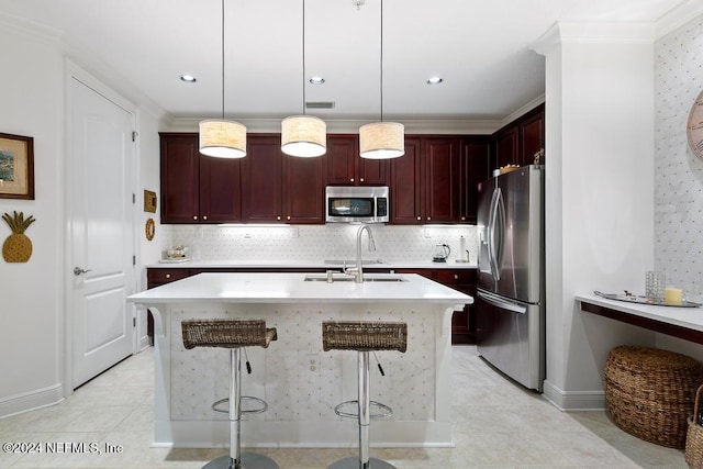 kitchen with hanging light fixtures, stainless steel appliances, an island with sink, a breakfast bar, and sink