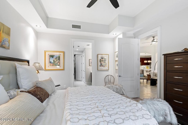 bedroom with light tile patterned floors, a tray ceiling, and ceiling fan