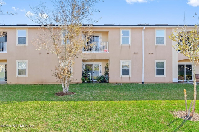 back of property with a balcony and a lawn