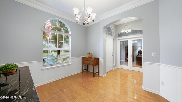 entrance foyer featuring french doors, light hardwood / wood-style floors, a notable chandelier, and crown molding