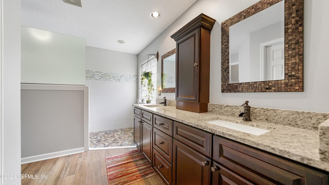 bathroom with vanity, a shower, a textured ceiling, and hardwood / wood-style floors