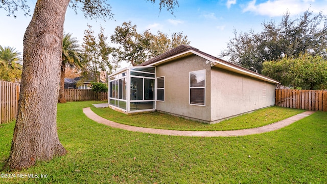 rear view of house with a lawn and a sunroom