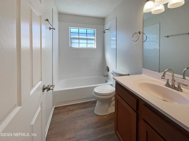 full bathroom with toilet, wood-type flooring, tiled shower / bath combo, vanity, and a textured ceiling