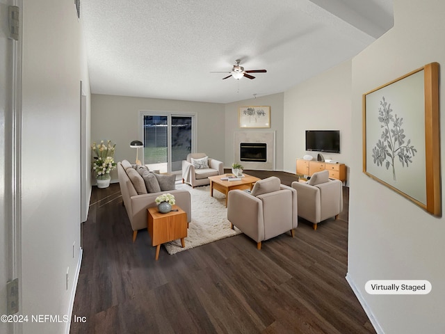 living room with a textured ceiling, ceiling fan, vaulted ceiling, and dark hardwood / wood-style flooring