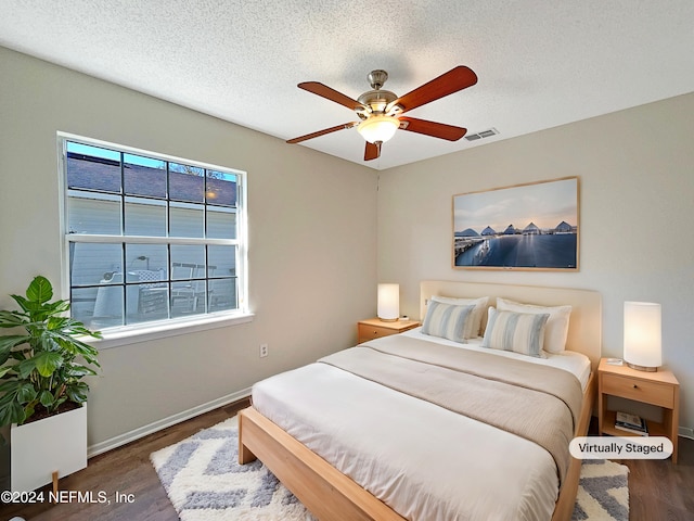 bedroom featuring a textured ceiling, dark wood-type flooring, and ceiling fan