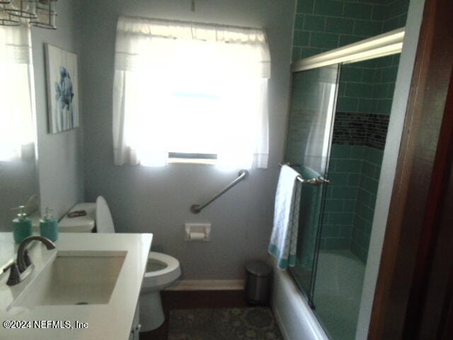 full bathroom with vanity, enclosed tub / shower combo, and toilet