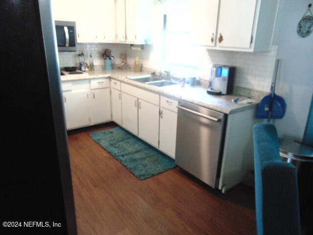 kitchen with appliances with stainless steel finishes, white cabinetry, sink, and dark wood-type flooring