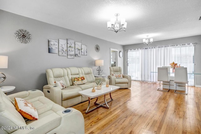 living room with a textured ceiling, light wood-type flooring, and a notable chandelier