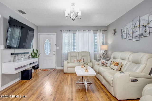 living room featuring light hardwood / wood-style floors, a textured ceiling, and a chandelier