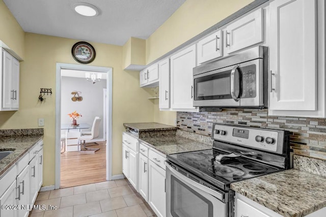 kitchen featuring stone counters, white cabinetry, light hardwood / wood-style floors, and appliances with stainless steel finishes