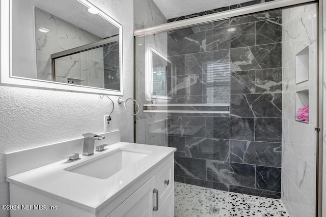 bathroom with a textured ceiling, vanity, and an enclosed shower