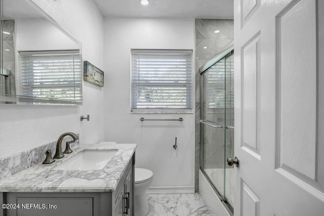 full bathroom with vanity, bath / shower combo with glass door, and toilet