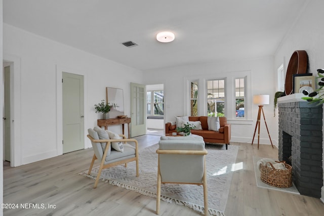 living room featuring crown molding, a fireplace, and light hardwood / wood-style floors