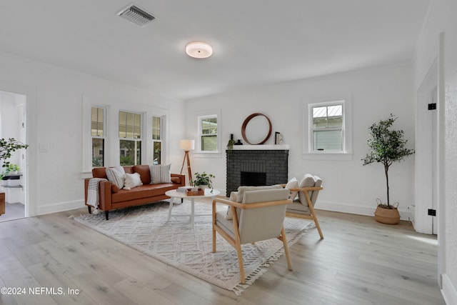 living room with light hardwood / wood-style flooring, a fireplace, and a healthy amount of sunlight