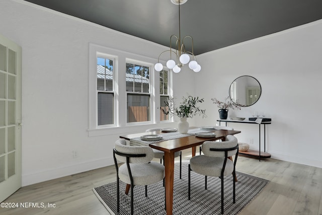 dining space featuring ornamental molding, a chandelier, and light hardwood / wood-style flooring