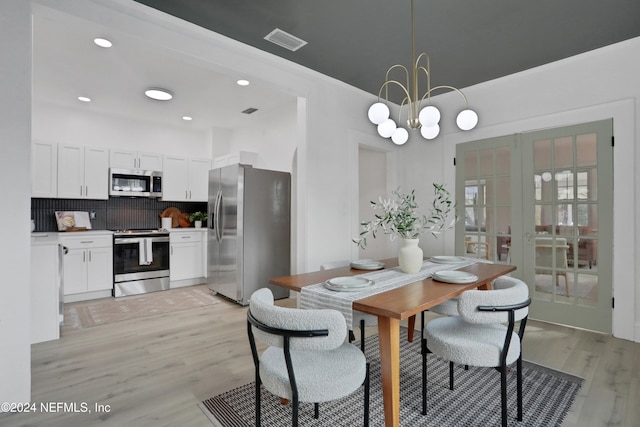 dining area with a chandelier, light wood-type flooring, and french doors