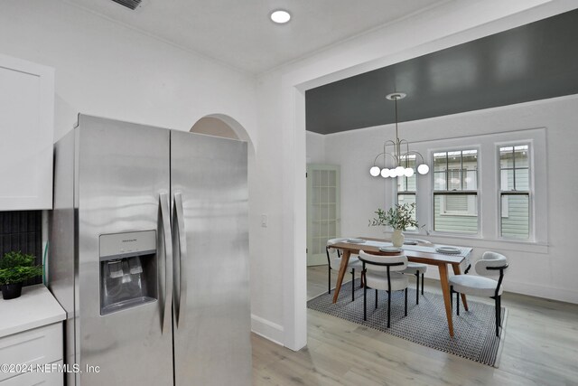 kitchen with hanging light fixtures, white cabinetry, light wood-type flooring, a notable chandelier, and stainless steel refrigerator with ice dispenser