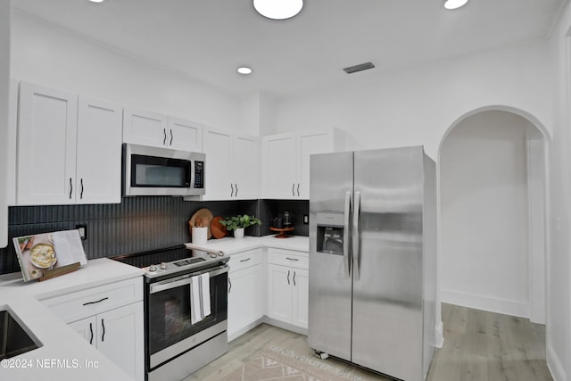 kitchen featuring stainless steel appliances, decorative backsplash, light hardwood / wood-style flooring, and white cabinets