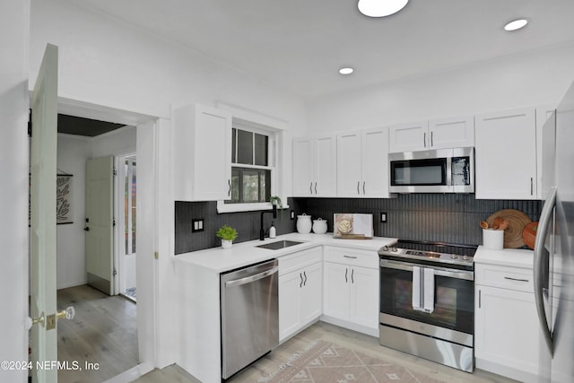 kitchen featuring white cabinetry, tasteful backsplash, appliances with stainless steel finishes, and sink