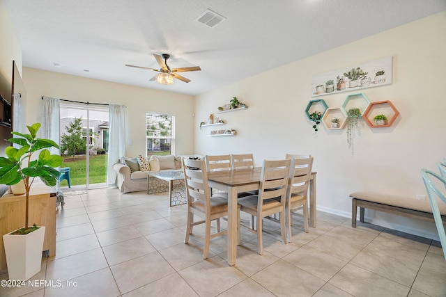 dining area featuring a textured ceiling, light tile patterned floors, and ceiling fan