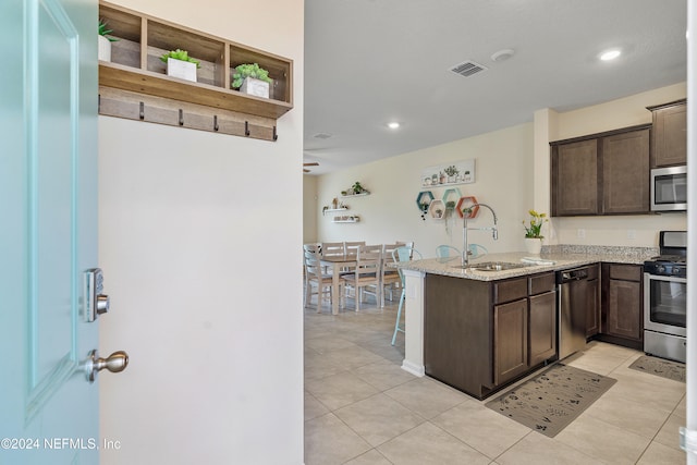 kitchen featuring kitchen peninsula, dark brown cabinetry, stainless steel appliances, and sink