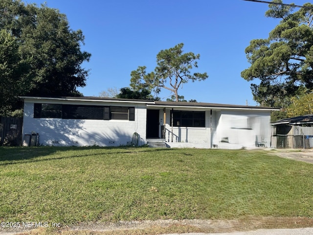 ranch-style house with entry steps, concrete block siding, and a front lawn