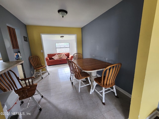 tiled dining room featuring baseboards