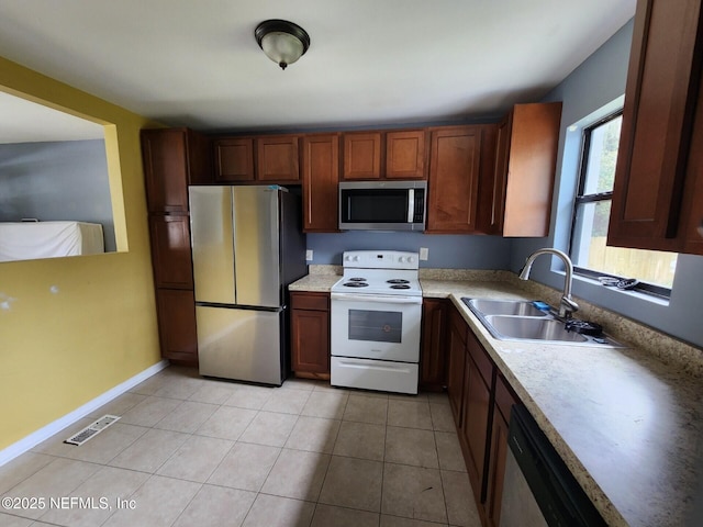 kitchen with baseboards, light countertops, light tile patterned floors, appliances with stainless steel finishes, and a sink