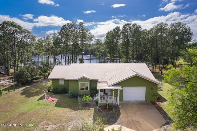 view of front of house with covered porch, a garage, a water view, and a front yard