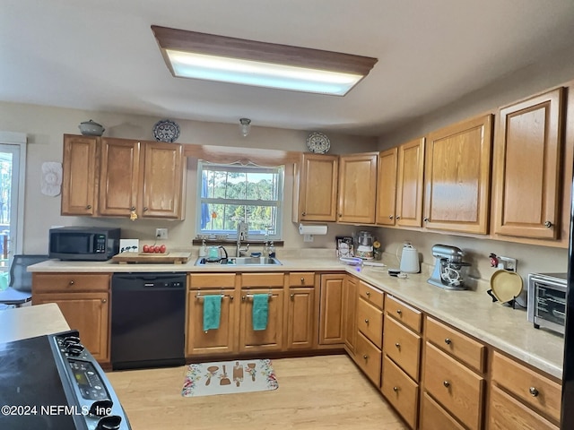 kitchen featuring plenty of natural light, black appliances, light hardwood / wood-style floors, and sink