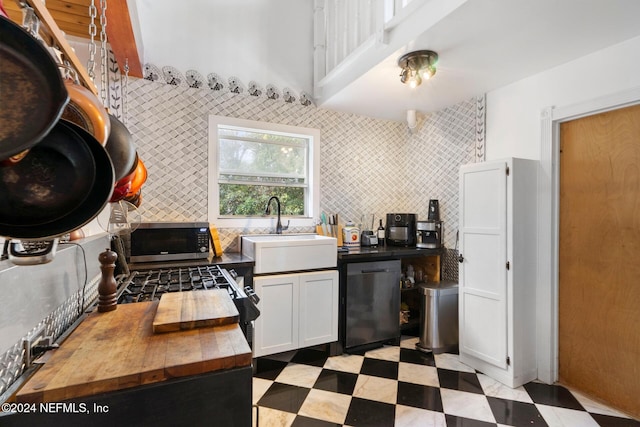 kitchen with sink, backsplash, white cabinetry, stainless steel appliances, and tile walls