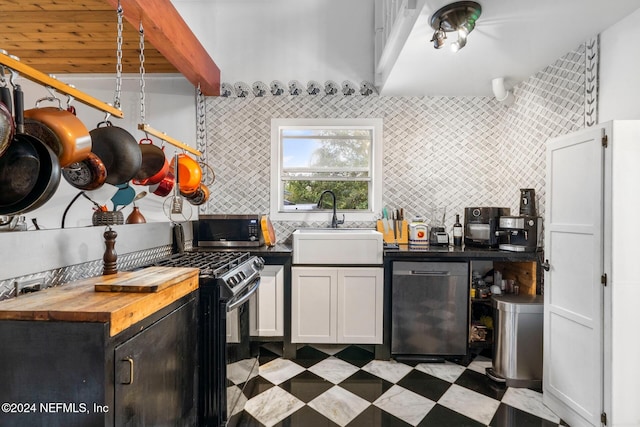 kitchen featuring appliances with stainless steel finishes, sink, backsplash, wood counters, and white cabinets