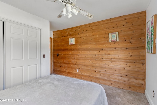 bedroom featuring a closet, ceiling fan, wood walls, and carpet floors