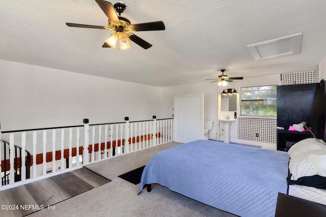 bedroom with ceiling fan, carpet flooring, a textured ceiling, and ensuite bath