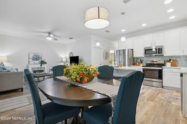 dining room featuring light hardwood / wood-style floors, crown molding, and ceiling fan