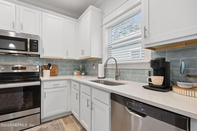 kitchen with stainless steel appliances, backsplash, crown molding, sink, and white cabinets