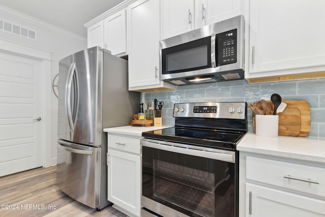 kitchen featuring ornamental molding, white cabinetry, appliances with stainless steel finishes, light hardwood / wood-style floors, and tasteful backsplash