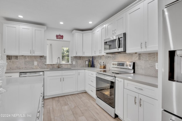 kitchen featuring light hardwood / wood-style flooring, stainless steel appliances, sink, white cabinets, and tasteful backsplash