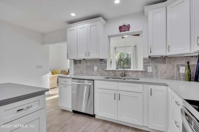 kitchen featuring dishwasher, sink, light wood-type flooring, white cabinets, and tasteful backsplash