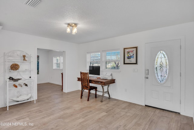 home office with light hardwood / wood-style flooring and a textured ceiling