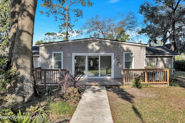 rear view of house featuring a wooden deck and a lawn