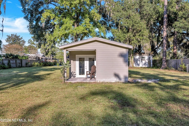 back of house with a patio, a storage shed, and a lawn