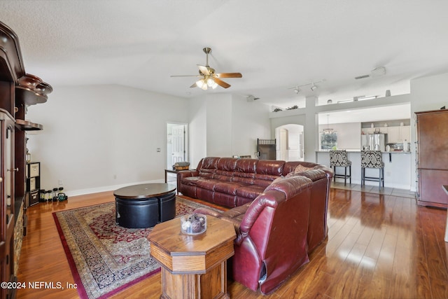 living room with lofted ceiling, a textured ceiling, hardwood / wood-style flooring, and ceiling fan