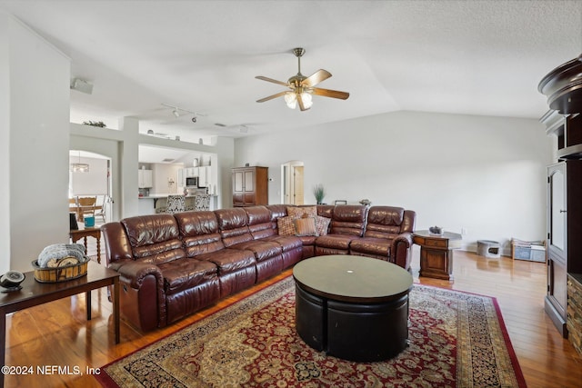 living room featuring a textured ceiling, vaulted ceiling, hardwood / wood-style flooring, and ceiling fan