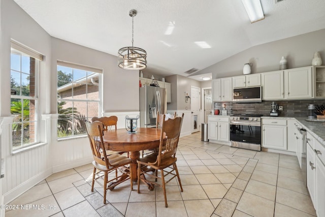 interior space with a chandelier, a textured ceiling, vaulted ceiling, and plenty of natural light